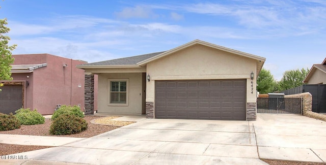 view of front of house featuring stucco siding, a garage, concrete driveway, stone siding, and a gate