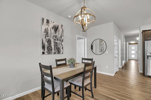 dining room featuring a chandelier, light wood finished floors, and baseboards