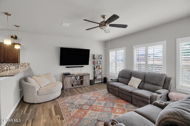living room featuring ceiling fan, light wood finished floors, and baseboards