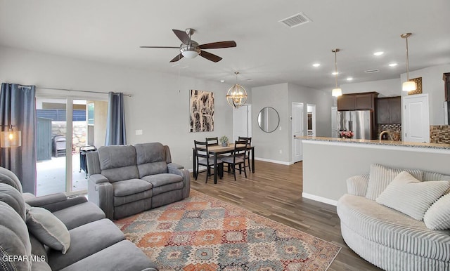 living room with a ceiling fan, recessed lighting, dark wood finished floors, a chandelier, and baseboards