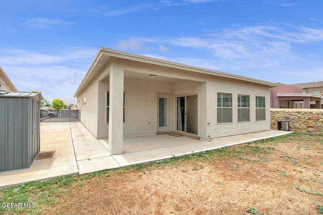 rear view of house with stucco siding, a patio, and fence