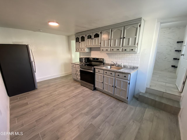 2805 Grant Ave, El Paso, TX 79930 - kitchen featuring appliances with stainless steel finishes, a sink, light wood-style flooring, backsplash, and baseboards