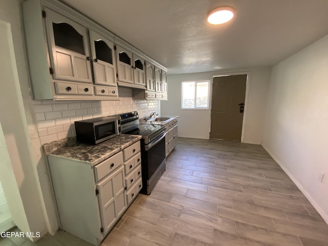 2805 Grant Ave, El Paso, TX 79930 - kitchen with stainless steel appliances, backsplash, a sink, wood tiled floors, and dark countertops
