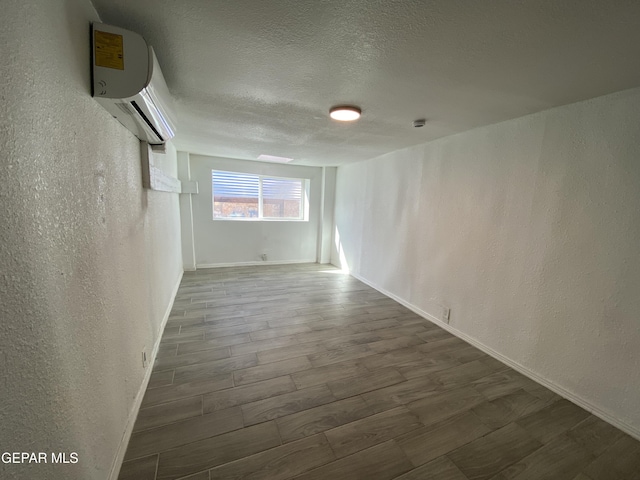 2805 Grant Ave, El Paso, TX 79930 - empty room with a textured wall, wood finished floors, a wall mounted AC, a textured ceiling, and baseboards