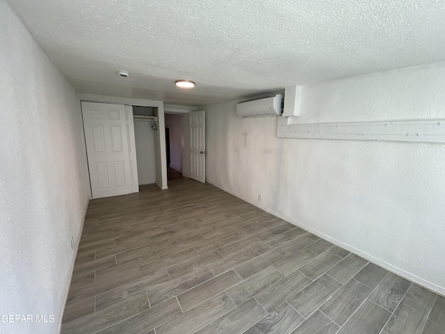 2805 Grant Ave, El Paso, TX 79930 - finished below grade area featuring a textured ceiling, wood tiled floors, an AC wall unit, a textured wall, and baseboards