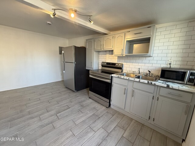 2805 Grant Ave, El Paso, TX 79930 - kitchen with appliances with stainless steel finishes, backsplash, a sink, and light wood finished floors