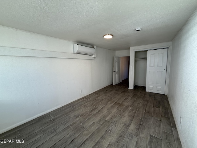 2805 Grant Ave, El Paso, TX 79930 - unfurnished bedroom featuring a wall unit AC, dark wood-type flooring, a textured ceiling, a closet, and baseboards