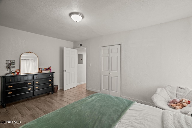 2805 Grant Ave, El Paso, TX 79930 - bedroom featuring wood tiled floors, a textured ceiling, a closet, electric panel, and baseboards