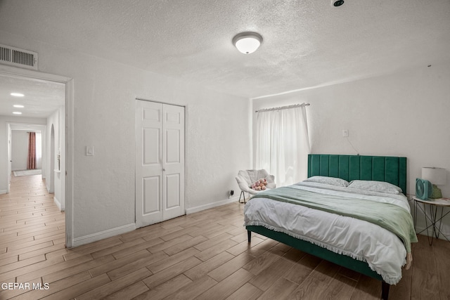 2805 Grant Ave, El Paso, TX 79930 - bedroom featuring a textured ceiling, wood tiled floors, baseboards, a closet, and multiple windows
