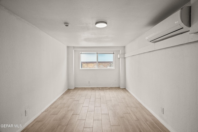2805 Grant Ave, El Paso, TX 79930 - unfurnished room featuring a wall unit AC, light wood-type flooring, a textured ceiling, and baseboards