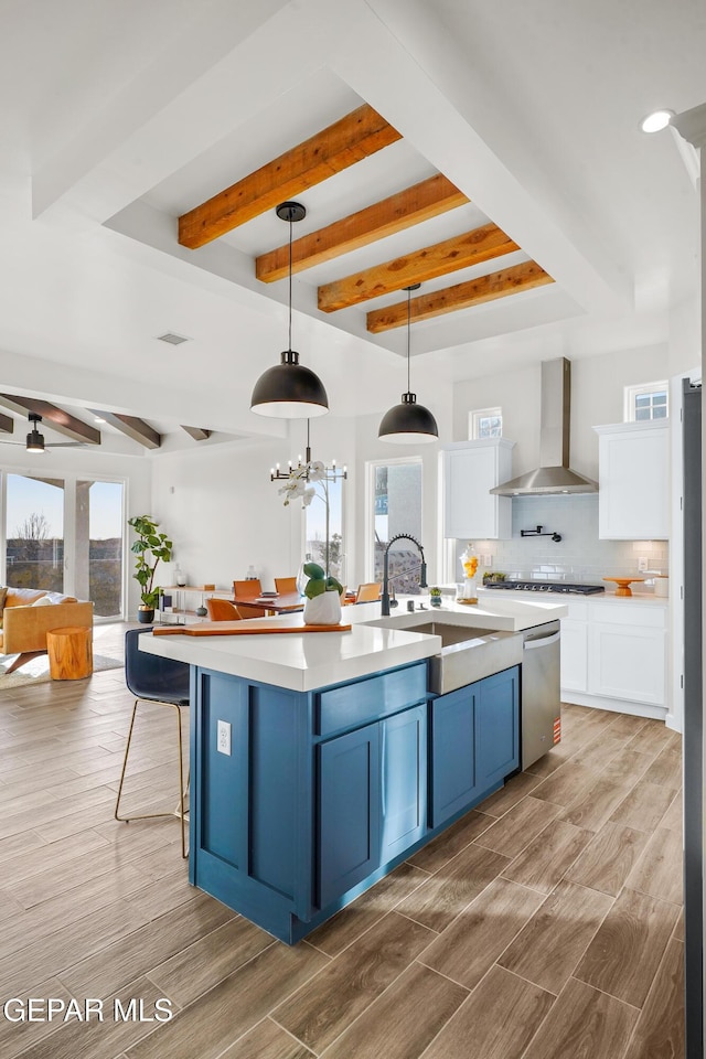 3829 Aspire Pl, El Paso, TX 79938 - kitchen featuring wall chimney range hood, a sink, blue cabinets, beam ceiling, and white cabinets