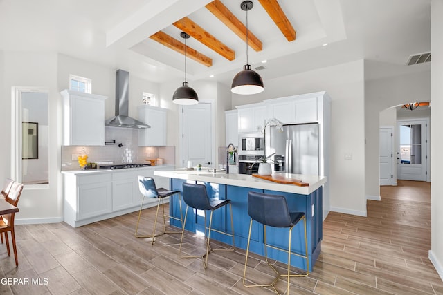 3829 Aspire Pl, El Paso, TX 79938 - kitchen with wall chimney exhaust hood, appliances with stainless steel finishes, beam ceiling, light wood finished floors, and light countertops