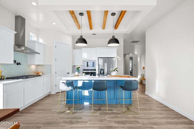 3829 Aspire Pl, El Paso, TX 79938 - kitchen featuring stainless steel appliances, wall chimney range hood, backsplash, white cabinetry, and beamed ceiling