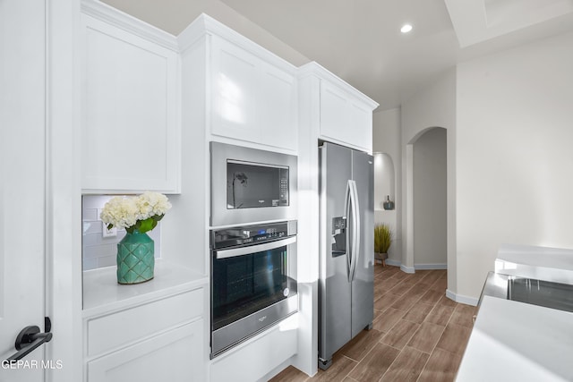 3829 Aspire Pl, El Paso, TX 79938 - kitchen featuring stainless steel appliances, baseboards, arched walkways, light countertops, and white cabinetry