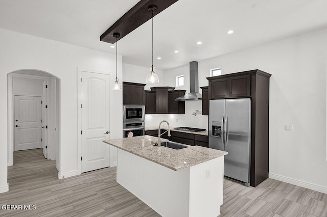 3825 Aspire Pl, El Paso, TX 79938 - kitchen featuring stainless steel appliances, a sink, arched walkways, dark brown cabinets, and wall chimney range hood
