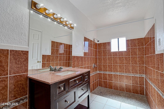 7701 Hermosillo Dr, El Paso, TX 79915 - bathroom featuring tile walls, tiled shower, vanity, tile patterned floors, and a textured ceiling