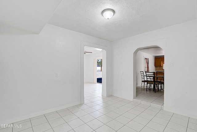 7701 Hermosillo Dr, El Paso, TX 79915 - empty room with arched walkways, light tile patterned flooring, a textured ceiling, and baseboards