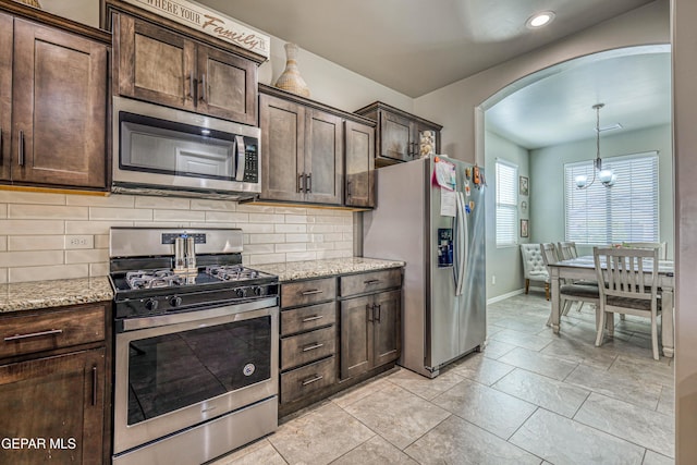 13729 Blackburn Ave, El Paso, TX 79928 - kitchen featuring stainless steel appliances, arched walkways, dark brown cabinetry, baseboards, and tasteful backsplash