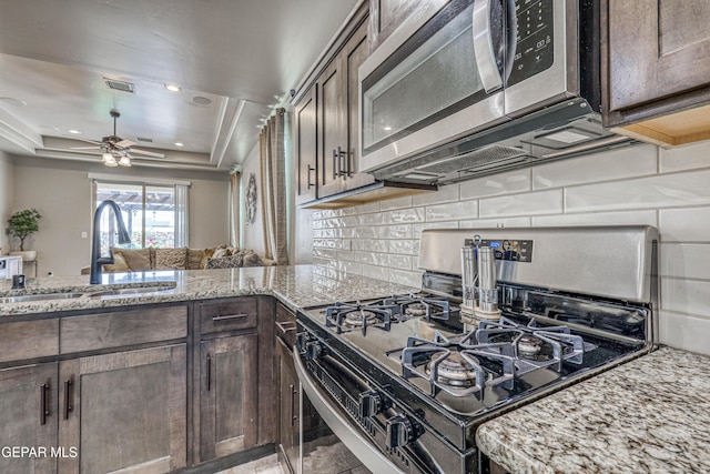 13729 Blackburn Ave, El Paso, TX 79928 - kitchen featuring appliances with stainless steel finishes, a sink, dark brown cabinets, backsplash, and a tray ceiling