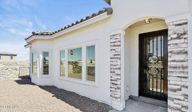556 Cedarwood Ave, El Paso, TX 79928 - doorway to property with stucco siding, stone siding, a tile roof, and fence