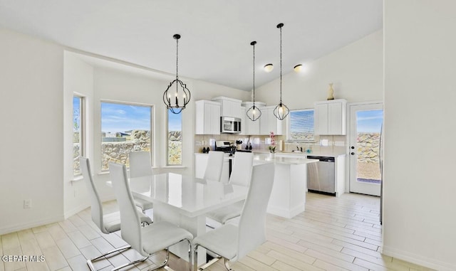 556 Cedarwood Ave, El Paso, TX 79928 - dining area featuring a chandelier, light wood-type flooring, high vaulted ceiling, and baseboards