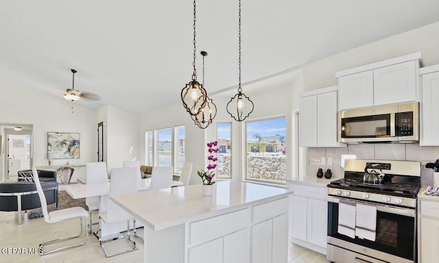 556 Cedarwood Ave, El Paso, TX 79928 - kitchen featuring appliances with stainless steel finishes, light countertops, a center island, tasteful backsplash, and white cabinets