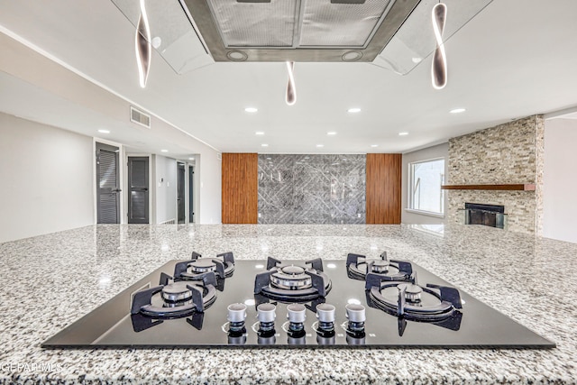 1957 Ratner Cir, El Paso, TX 79936 - kitchen view of black stovetop, recessed lighting, tasteful backsplash, light stone countertops, and a fireplace