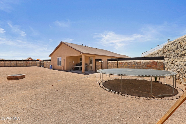 513 Bogota Pl, El Paso, TX 79928 - rear view of house featuring a trampoline, a fenced backyard, and an outdoor fire pit