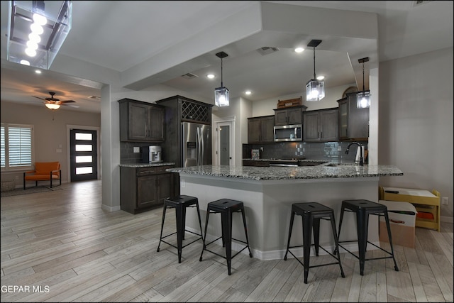 937 Grandevole Dr, El Paso, TX 79932 - kitchen featuring stainless steel appliances, light stone counters, light wood-style flooring, and a peninsula