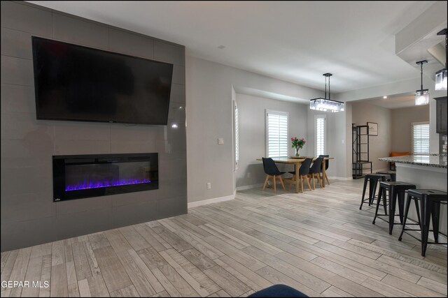 937 Grandevole Dr, El Paso, TX 79932 - living room with light wood-type flooring, a large fireplace, and baseboards