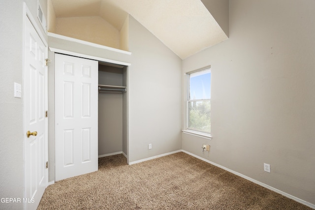 unfurnished bedroom with lofted ceiling, carpet floors, a closet, and baseboards