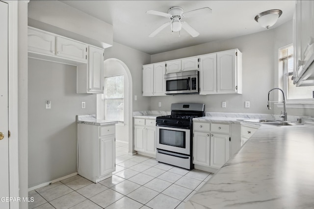 kitchen with appliances with stainless steel finishes, a sink, white cabinets, a ceiling fan, and light tile patterned floors
