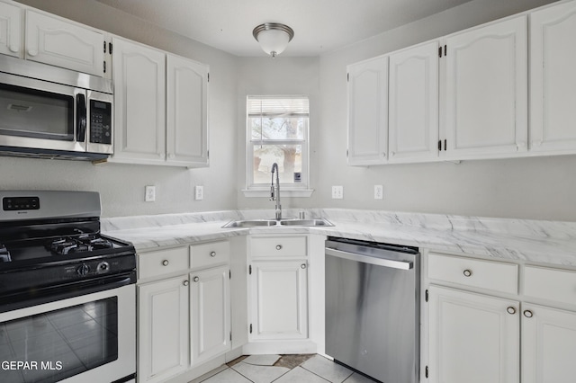 kitchen with appliances with stainless steel finishes, a sink, and white cabinetry