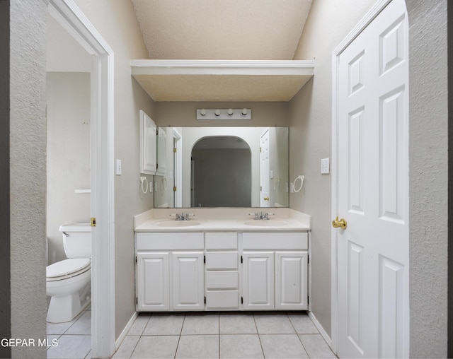 bathroom with tile patterned floors, double vanity, toilet, and baseboards