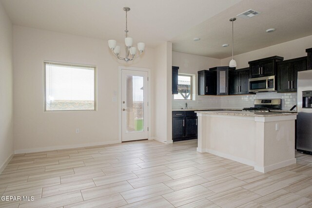 2240 Tierra Delmonte Dr, El Paso, TX 79938 - kitchen with stainless steel appliances, dark cabinetry, backsplash, and a chandelier