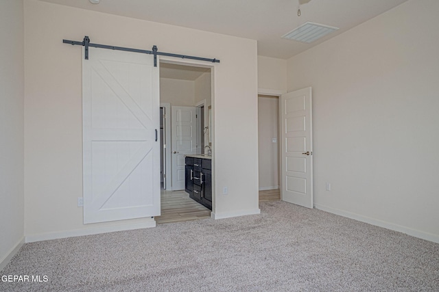 2240 Tierra Delmonte Dr, El Paso, TX 79938 - unfurnished bedroom featuring light colored carpet, a barn door, baseboards, and ensuite bathroom
