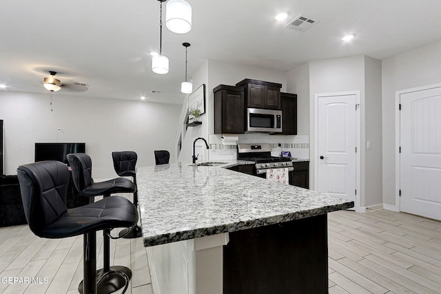 3516 Essence St, El Paso, TX 79938 - kitchen with appliances with stainless steel finishes, a kitchen breakfast bar, a peninsula, a sink, and light wood-style flooring