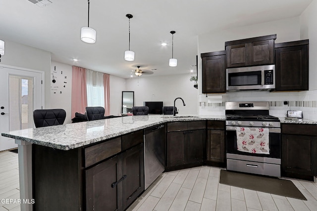 3516 Essence St, El Paso, TX 79938 - kitchen featuring stainless steel appliances, a sink, open floor plan, light stone countertops, and a peninsula