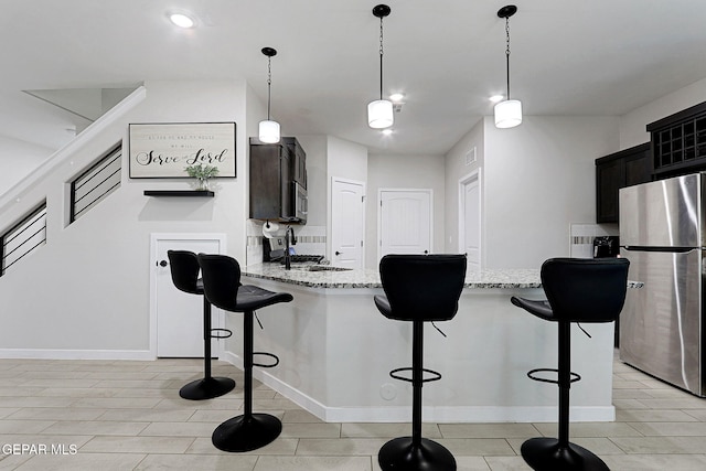 3516 Essence St, El Paso, TX 79938 - kitchen with stainless steel appliances, a breakfast bar, light stone counters, a peninsula, and decorative light fixtures
