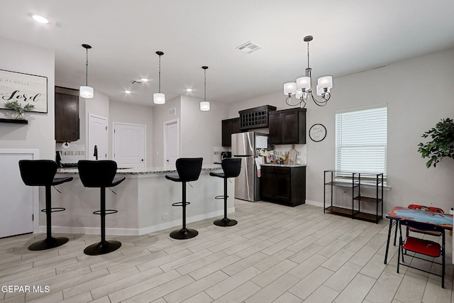 3516 Essence St, El Paso, TX 79938 - kitchen featuring freestanding refrigerator, a kitchen breakfast bar, a peninsula, light stone countertops, and baseboards