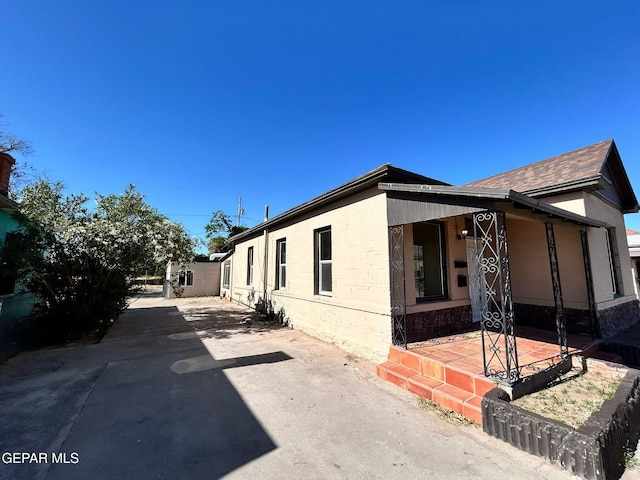 3416 Rivera Ave, El Paso, TX 79905 - view of side of property with a porch, brick siding, and driveway