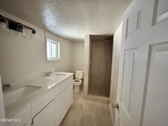 3416 Rivera Ave, El Paso, TX 79905 - bathroom with toilet, a textured ceiling, wood finished floors, a stall shower, and double vanity