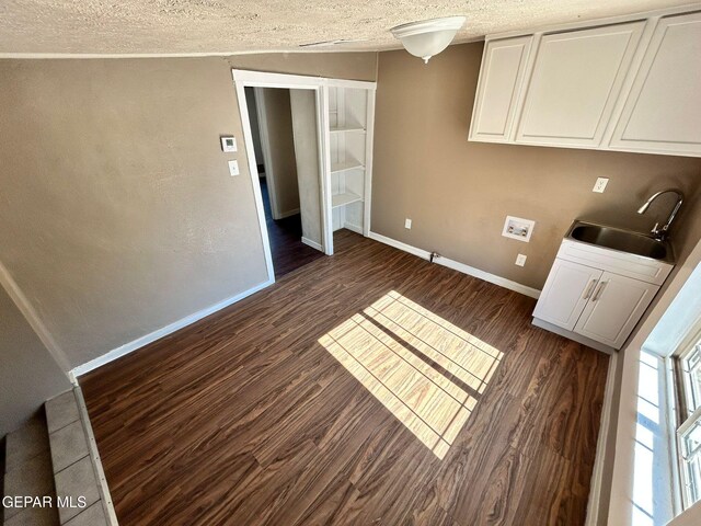 3416 Rivera Ave, El Paso, TX 79905 - laundry room with a textured ceiling, dark wood-type flooring, baseboards, and cabinet space