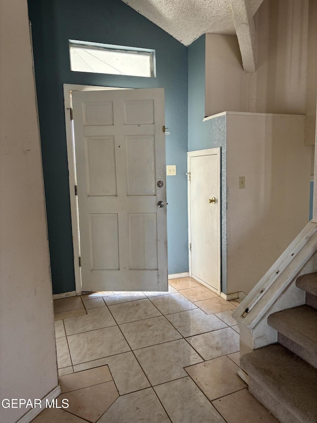10645 Obsidian St, El Paso, TX 79924 - entrance foyer featuring a textured ceiling, vaulted ceiling, light tile patterned floors, and stairs