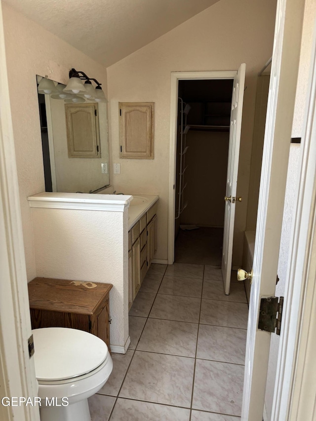 10645 Obsidian St, El Paso, TX 79924 - full bath with lofted ceiling, vanity, toilet, tile patterned floors, and a walk in closet
