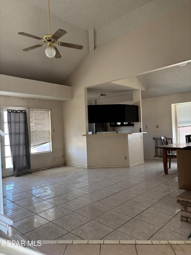 10645 Obsidian St, El Paso, TX 79924 - unfurnished living room with a textured ceiling, plenty of natural light, tile patterned floors, ceiling fan, and high vaulted ceiling
