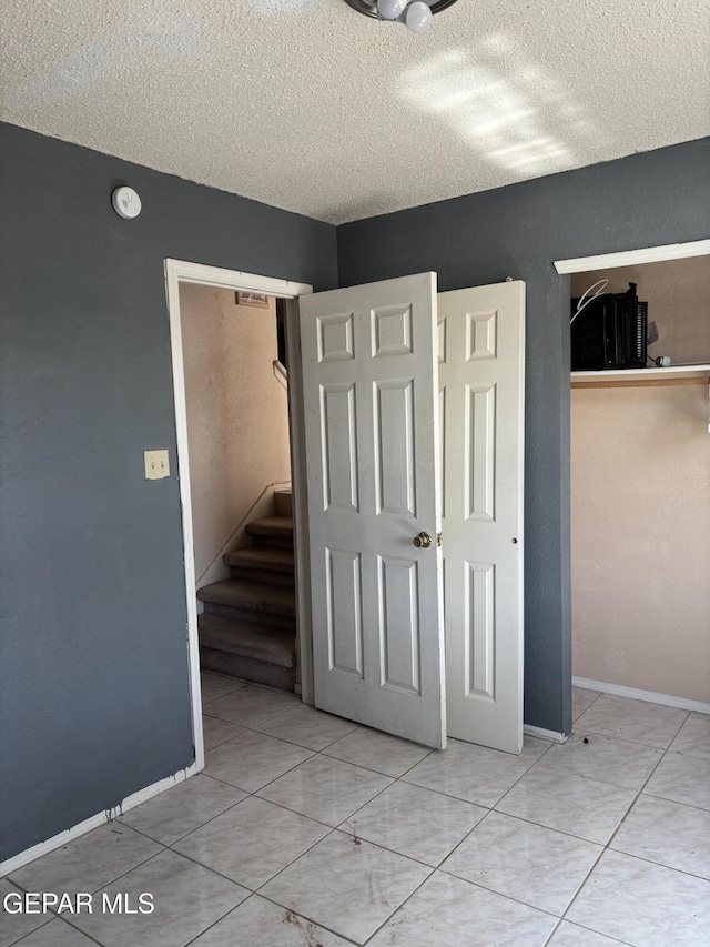 10645 Obsidian St, El Paso, TX 79924 - unfurnished bedroom with a closet, a textured ceiling, tile patterned flooring, and baseboards