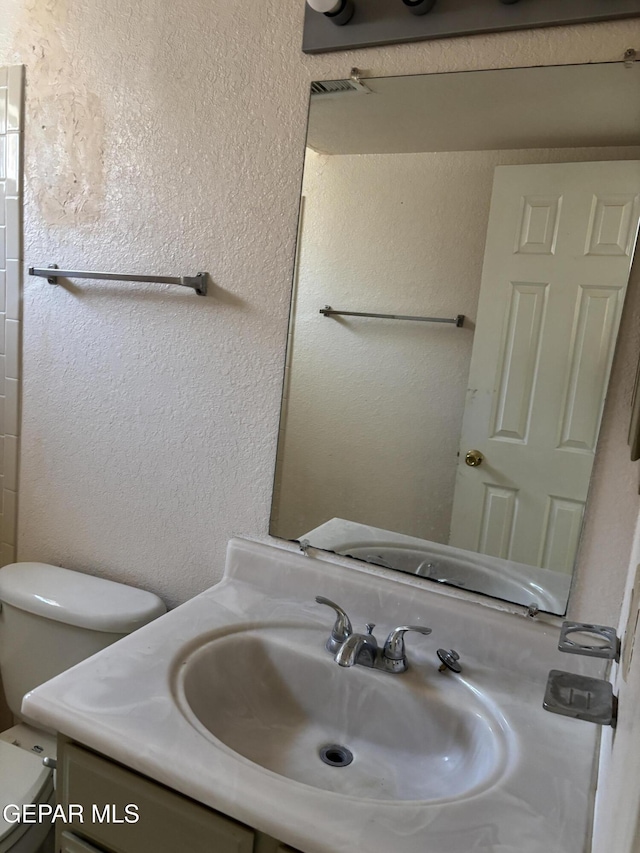 10645 Obsidian St, El Paso, TX 79924 - bathroom with vanity, toilet, and a textured wall