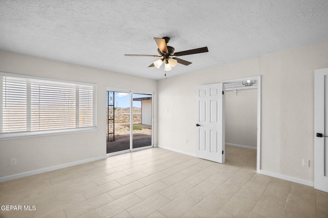 5325 Timberwolf Dr, El Paso, TX 79903 - unfurnished bedroom with access to outside, a textured ceiling, a spacious closet, and baseboards