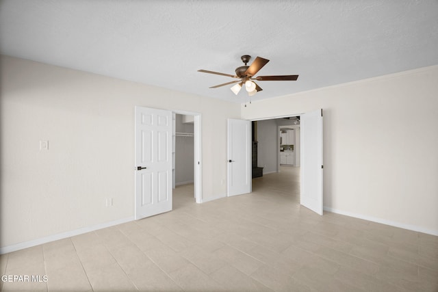5325 Timberwolf Dr, El Paso, TX 79903 - unfurnished bedroom with a walk in closet, baseboards, a ceiling fan, a closet, and a textured ceiling